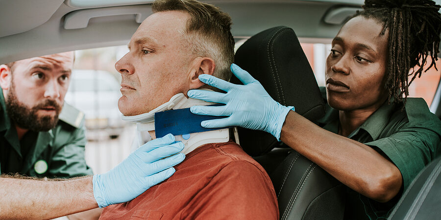 Paramedic placing a cervical collar to an injured man from car accident